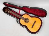 une guitare dans un étui, posée sur une surface blanche