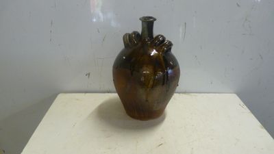 un vase marron posé sur une table blanche