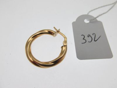un gros plan sur une petite boucle d'oreille en or en forme d'anneau, avec son étiquette de prix