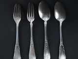 four silver spoons and a fork on a black surface