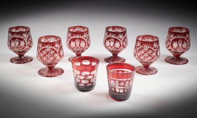 six verres à pied rouges sont alignés sur une surface blanche