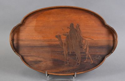une image représentant un plateau en bois sur lequel figure l'image d'un homme et de deux chameaux
