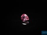 un diamant rose sur une surface noire dans l'obscurité