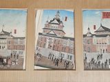 three paintings on the wall of a building with a clock tower