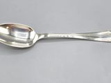 silver spoon with a spoon handle on a gray surface