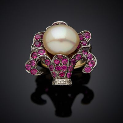 a white pearl and pink sapphire ring on a black surface