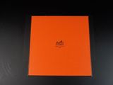 une boîte orange posée sur une surface noire, avec un fond noir