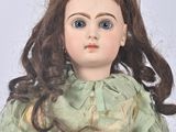 a doll that is wearing a green dress and holding a book