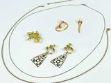 un gros plan d'un collier, de boucles d'oreilles et d'une bague posés sur une surface blanche