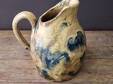 a brown and blue pitcher sitting on a wooden table