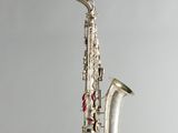 un saxophone argenté suspendu à une ficelle sur un mur gris