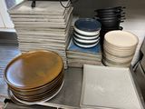 many plates and pans stacked on a kitchen counter