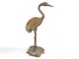 statue d'une grue debout sur un rocher, posée sur un fond blanc