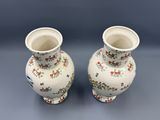 deux vases blancs ornés de fleurs, posés sur une table