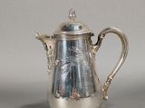 a silver coffee pot with a handle on a table