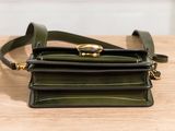 a close up of a small green purse on a wooden table