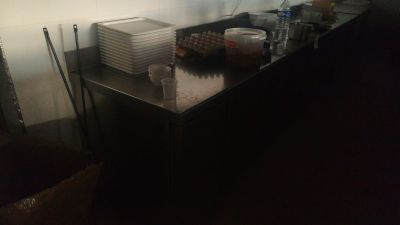 un plan de travail de cuisine faiblement éclairé, sur lequel sont posés de la vaisselle et des ustensiles