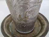 a silver vase sitting on top of a saucer