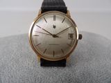 a gold wrist watch with a black leather strap