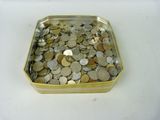 un récipient métallique rempli de pièces de monnaie posé sur une surface blanche