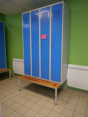 two blue lockers in a green room with a bench