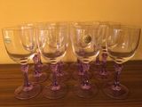 six verres à vin posés sur une table en bois près d'un mur