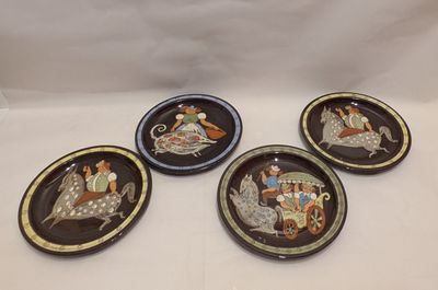 four plates with a picture of people on them on a white surface