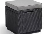 un pouf en osier noir surmonté d'un coussin gris