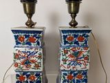 pair of blue and white vases with flowers on them sitting on a table