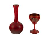 un vase rouge et un verre à vin posés l'un à côté de l'autre
