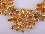 gold plated flower necklace with clear stones on a white surface