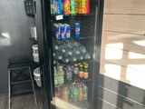 un réfrigérateur contenant des boissons et des sodas, situé dans une pièce