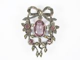 a close up of a brooch with a pink stone in it