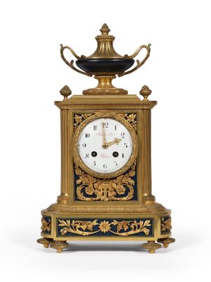 une horloge dorée et noire surmontée d'un bol noir