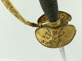 a close up of a gold plated sword with a black handle
