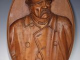 plaque en bois sculptée représentant un homme portant un chapeau et un manteau