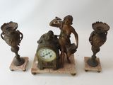 three bronze figurines with a clock on top of them