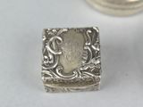 a small silver box sitting on a table next to a coin