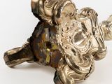 a silver figurine that is on a white surface