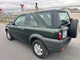 une voiture verte garée sur un parking, avec un sac à l'arrière