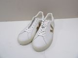white leather sneakers with gold detail and laces on a white surface