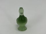a small green glass figurine sitting on a white surface