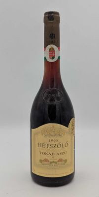 une vieille bouteille de vin rouge posée sur une table blanche