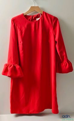 a red dress hanging on a hanger against a white wall