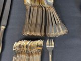 a lot of silverware on a table with a blue table cloth