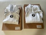 pair of white t - shirts in boxes on a white surface