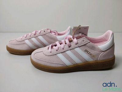 baskets Adidas roses et blanches avec des semelles en caoutchouc sur une base blanche