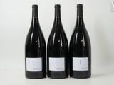 three bottles of red wine sit on a white surface next to each other