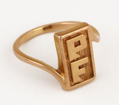un gros plan d'une bague en or sur laquelle figure la lettre « e »