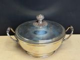 an antique silver plated bowl with a lid on a wooden table